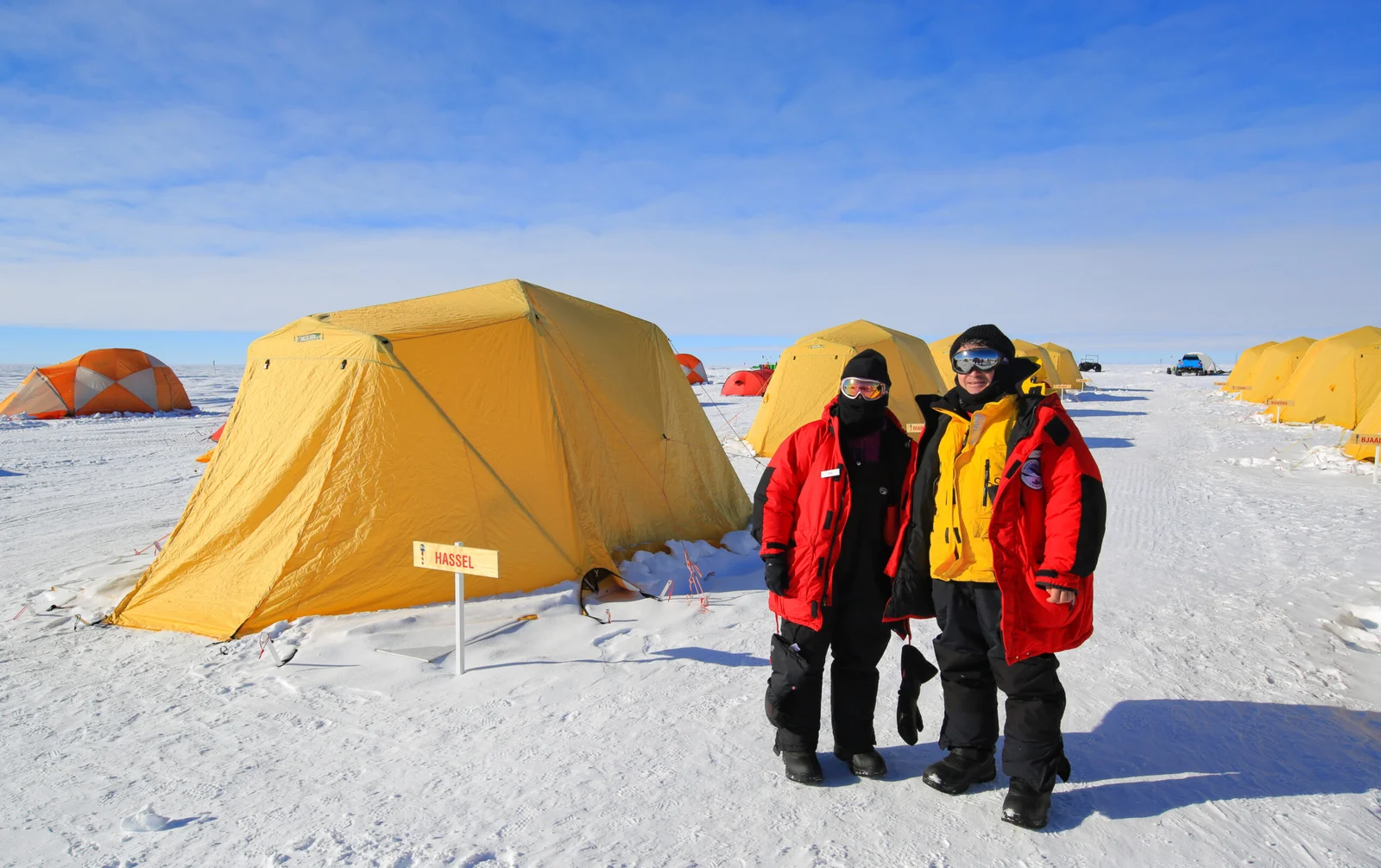 Guests dressed in polar layers pose for a photo outside one of the "Arctic Oven" guest tents, at ALE's South Pole Camp